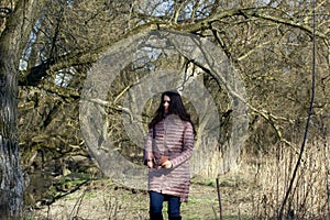 A girl walks through the spring park. In the hands of a smartphone. Searches for a subject to take pictures