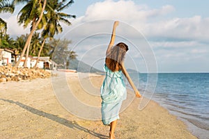 Girl walks on a tropical beach in a dres