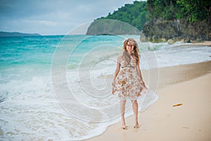 The girl walks on the water`s edge on the Boracay