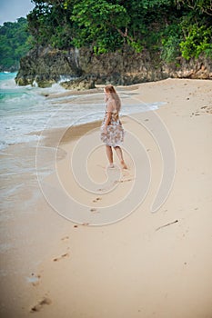 The girl walks on the water`s edge on the Boracay