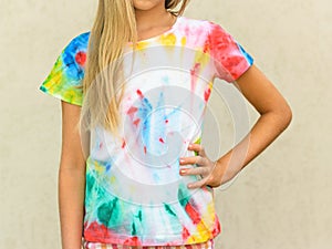 Girl at the wall in a t-shirt painted in the style of tie dye.