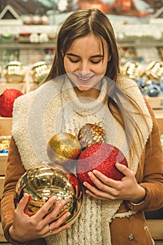 Girl in a warm coat holding large ball for Christmas tree in a mall at the Christmas Fair