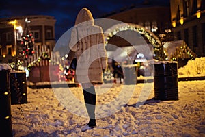 Girl in a warm fur mink coat walking in a snowy city.