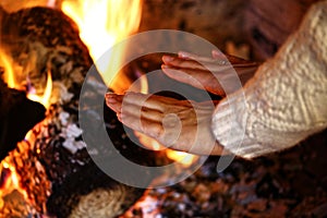 Girl warm her hands over fire in winter