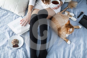 Girl with warm socks with a cup of tea, cat, close the book