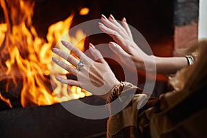 Girl is warming her hands by the fire