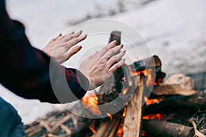 Girl warms hands near a fire in winter