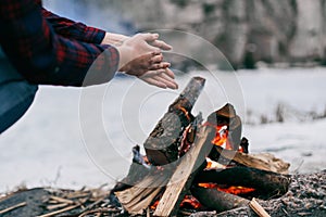 Girl warms hands near a fire in winter