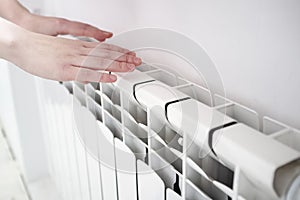 Girl warms hands near a radiator