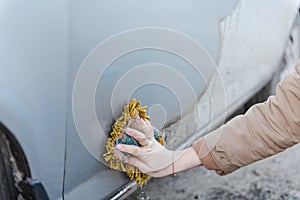 A girl washes a car. To wash the car with a sponge. Foam by car. Clean car