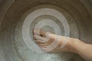 girl washes her feet in a basin of water on the wooden floor at home, foot care, wash feet at home, hygiene, swim