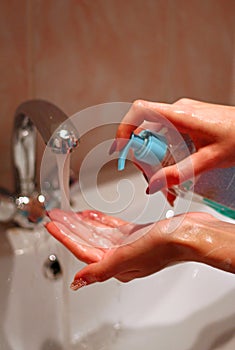 Girl washes her hands with liquid soap