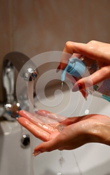Girl washes her hands with liquid soap