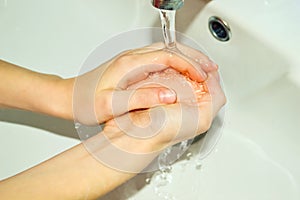 a girl washes her hands with soap in the sink