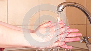 The girl washes her hands with warm water and soap after a walk to prevent germs or viruses from getting through dirty