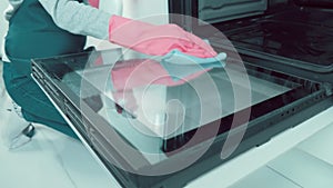 The girl washes the kitchen door inside the oven with detergent, spray.