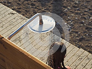 The girl washes under a summer shower outdoors on a sunny day. Beach shower