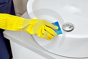 Girl washes a white sink in the bathroom. House cleaning.