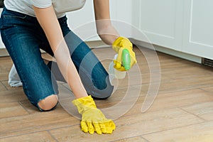 A girl is washing a floor in yellow gloves. A girl is cleaning a room with detergents