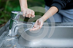 Girl washing her hands at the park. Baby try to turn off water faucet. A child`s hand turning off the tap. Save water. World Wate