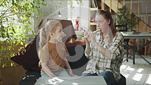 The girl watches her mother play the flute, laughs and covers her ears