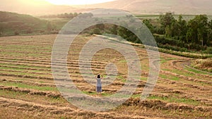 Girl watches the sunset on the agricultural field with harvested wheats.