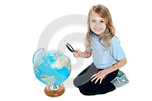 Girl watching globe through magnifying glass