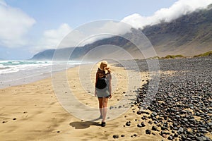 Girl is watching the suggestive landscape of Caleta Famara, Lanzarote, Canary Islands