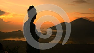 Girl watching sunrise over Lake Batur, Volcano Agung and Abang, Bali, Indonesia