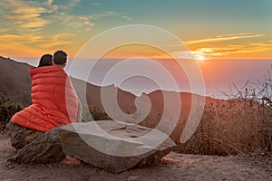 Girl watching Sunset while Draped in blanket