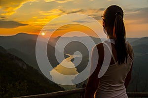 Girl watching sunset from the top of the mountain