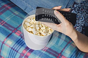 Girl watching tv with popcorn at home in the living room. The concept of laziness photo