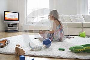 Girl Watching TV With Toys On Floor