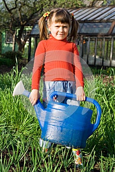 Girl with watering can on the vegetable garden