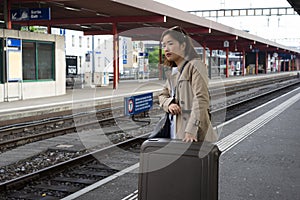 A girl is wating a train in a trian station at Geneva, Switzerland.