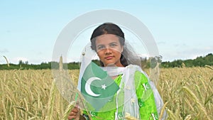 Girl waving flag of Pakistan outdoors . Happy independence day of Pakistan.