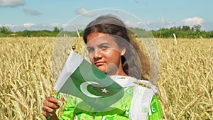 Girl waving flag of Pakistan outdoors . Happy independence day of Pakistan.