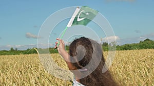 Girl waving flag of Pakistan outdoors . Happy independence day of Pakistan.