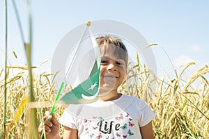 Girl waving flag of Pakistan outdoors over blue cloudy sky and golden wheat.