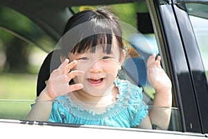 Girl waving goodbye in a car.