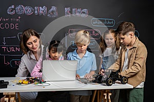 Girl wear pink cloth use laptop for coding while teacher watch her. Erudition.