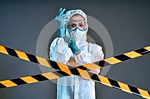 Girl wearing antiviral protective uniform putting on rubber gloves behind barrier tape-quarantine