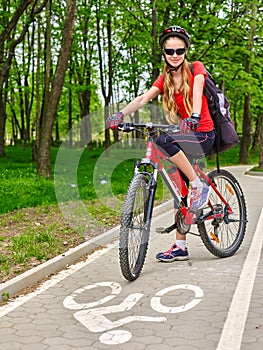 Girl wearing bicycle helmet and rucksack ciclyng road bicycle.
