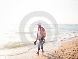 Girl wearing Blue jeans and red plaid shirt and backpacking yellow doing walking on the sea