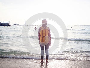 Girl wearing Blue jeans and red plaid shirt and backpacking yellow doing walking on the sea