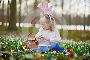 Girl wearing bunny ears playing egg hunt on Easter