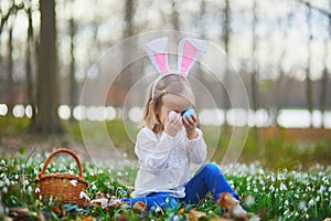 Girl wearing bunny ears playing egg hunt on Easter