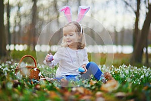 Girl wearing bunny ears playing egg hunt on Easter