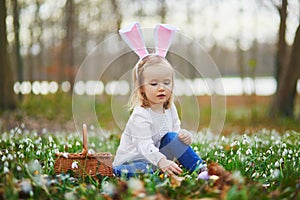Girl wearing bunny ears playing egg hunt on Easter