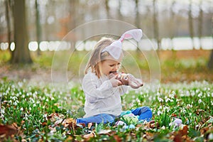 Girl wearing bunny ears playing egg hunt on Easter